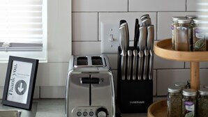 Een keuken met een broodrooster, een messenblok en potten met kruiden op het aanrecht.