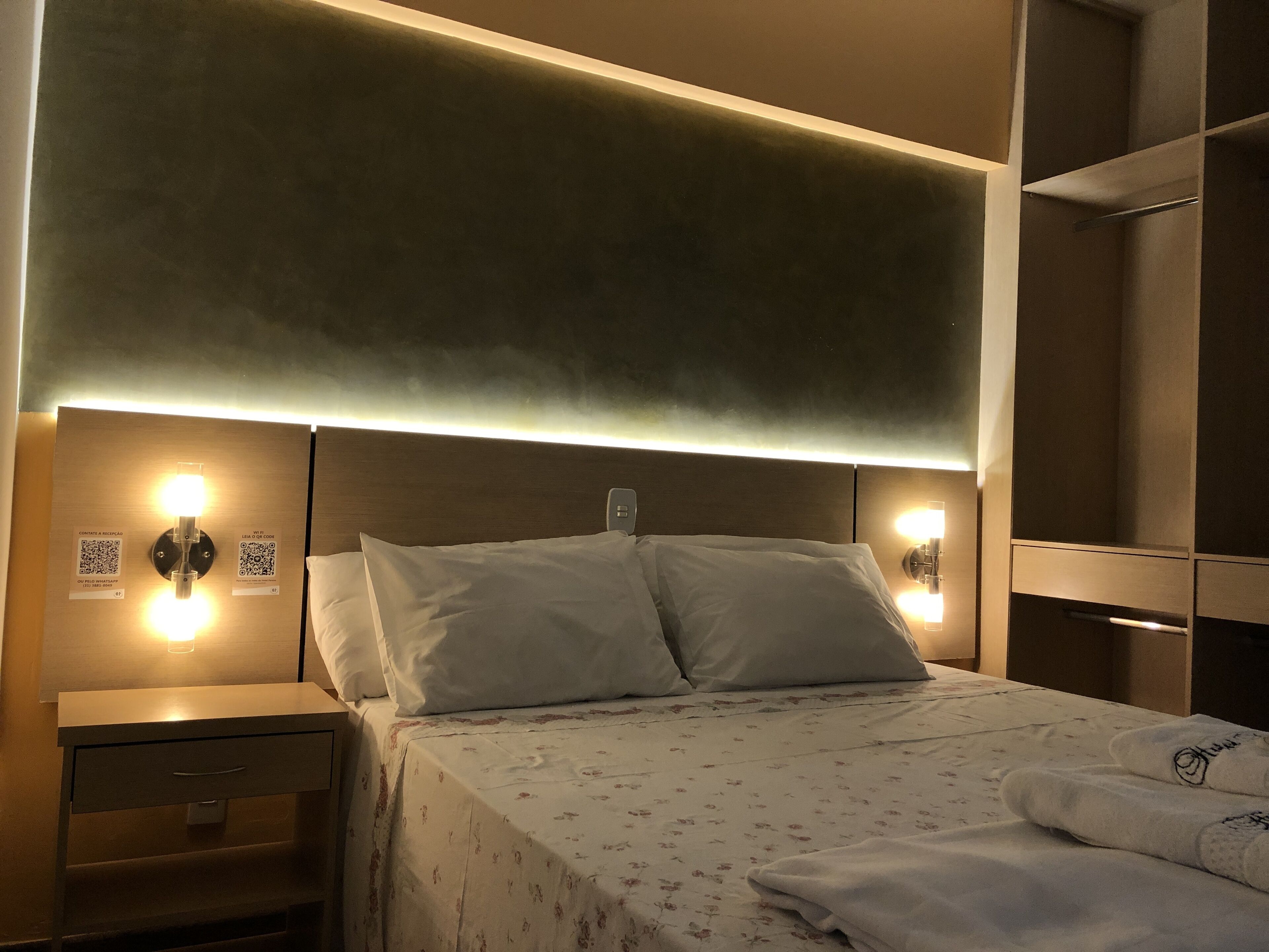 A hotel room with a bed, nightstands, and wall-mounted lights.