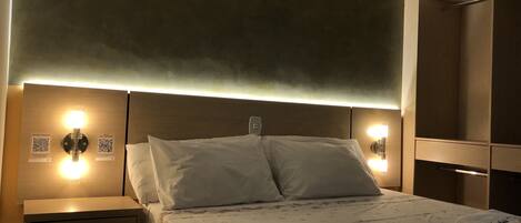 A hotel room with a bed, nightstands, and wall-mounted lights.