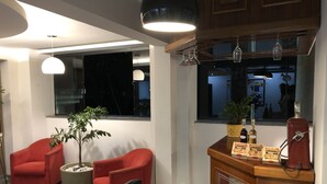 A modern living room with a red sofa, a black leather chair, and a wooden coffee table with a potted plant. - Hotel e Restaurante Paraíso Ponte Nova - Ponte Nova - MG (Ponte Nova)