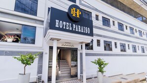 A hotel entrance with a sign reading "HOTEL PARAISO," a staircase leading inside, and two potted plants on either side. - Hotel e Restaurante Paraíso Ponte Nova - Ponte Nova - MG (Ponte Nova)