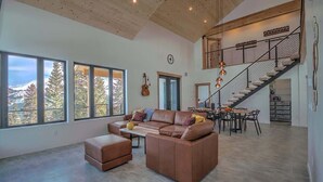 A spacious living area with a large window, a staircase, and a dining area. - Hot Tub Haven with Panoramic View | Blue River (Breckenridge)