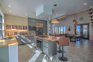 Une cuisine moderne dotée d’un îlot central, d’appareils électroménagers intégrés et d’un coin repas avec une grande fenêtre.
