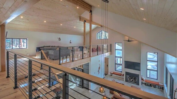 A spacious interior with a high ceiling, wooden beams, a staircase, and large windows. - Hot Tub Haven with Panoramic View | Blue River (Breckenridge)