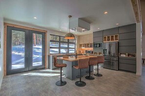 A modern kitchen with a central island, bar stools, and built-in appliances.
