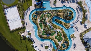 An aerial view of a resort with a winding pool, multiple lounge areas, and a separate building with a pool.