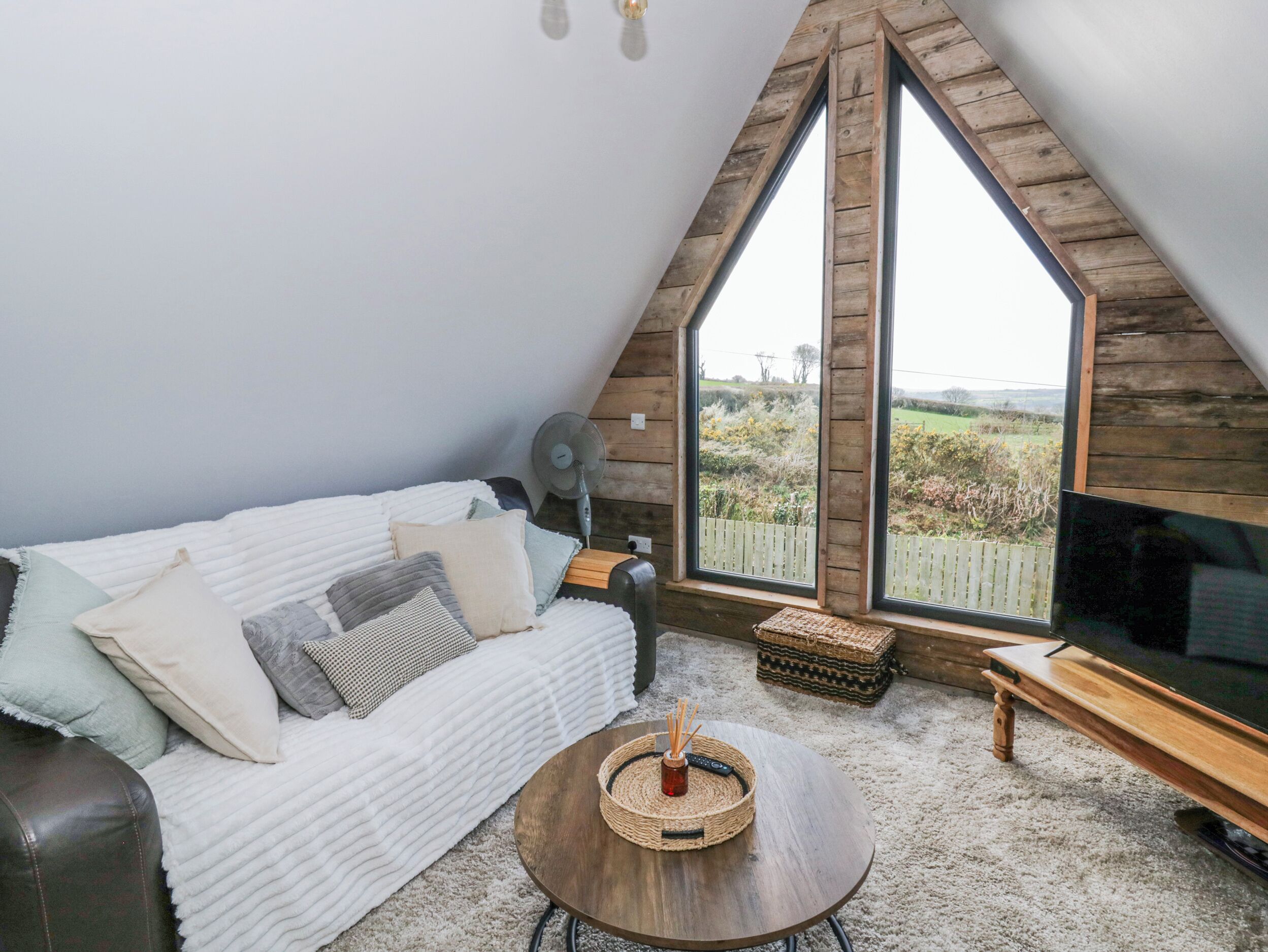 Une chambre confortable aménagée en mezzanine, avec une grande fenêtre, un canapé, une télévision et une petite table.