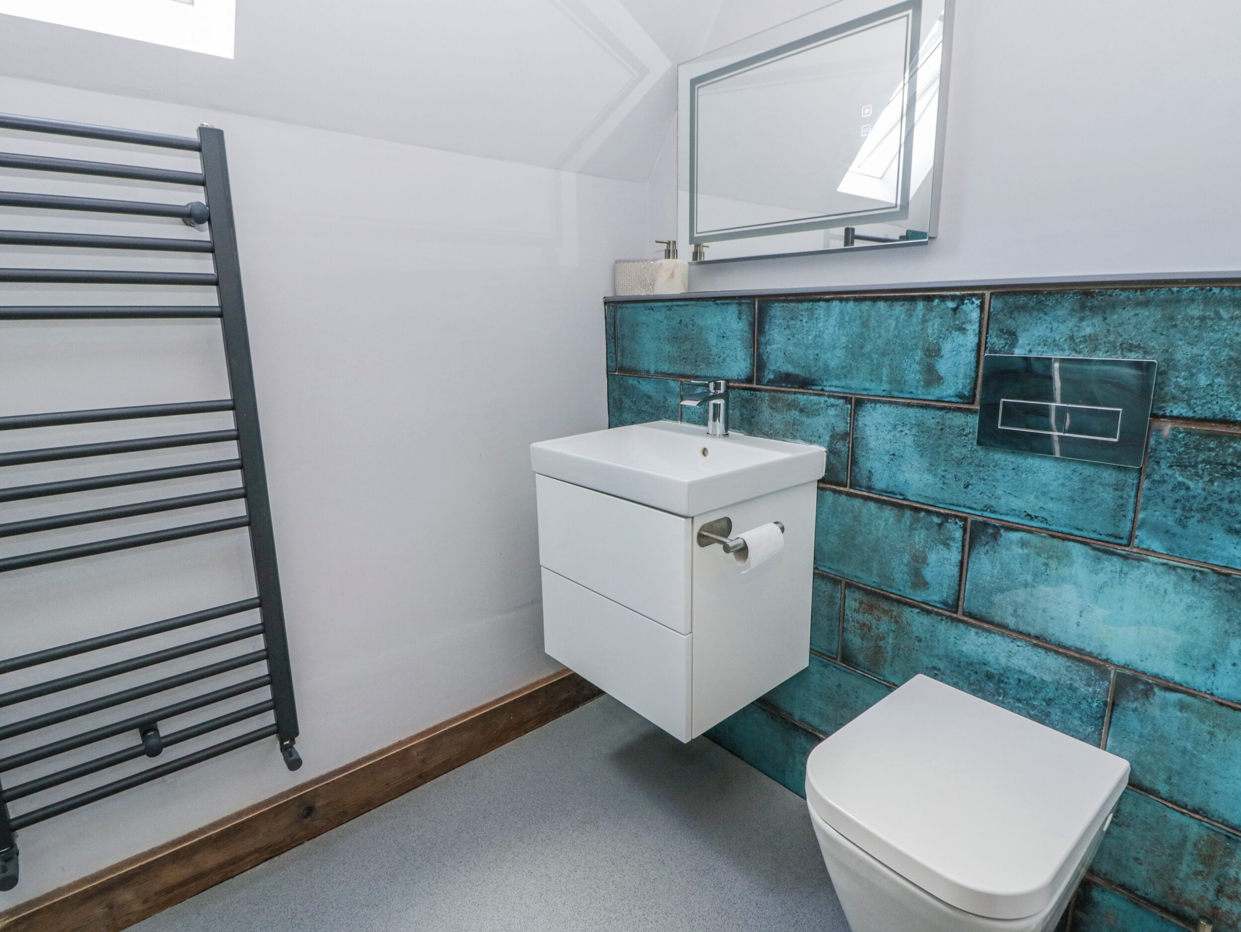 A bathroom with a white sink, a toilet, a towel rack, and a mirror.