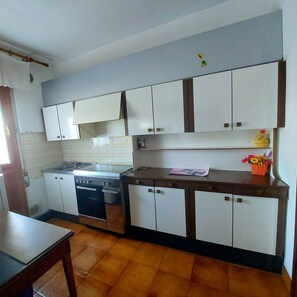 Een koelkast, een kookplaat, kookgerei, borden en bestek