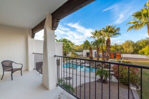 A balcony with a pool, palm trees, and a chair. - Serene in Scottsdale-5BR w/Pool, Hot Tub + Gym (Scottsdale)