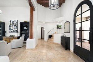 A spacious living area with a high ceiling, a staircase, and a large arched window. - Serene in Scottsdale-5BR w/Pool, Hot Tub + Gym (Scottsdale)