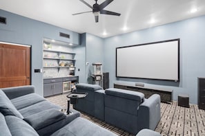 A home theater room with a large screen, comfortable seating, and a small kitchen area. - Serene in Scottsdale-5BR w/Pool, Hot Tub + Gym (Scottsdale)