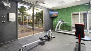 A gym with exercise equipment, a treadmill, and a television on the wall. - Serene in Scottsdale-5BR w/Pool, Hot Tub + Gym (Scottsdale)
