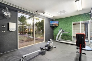 A gym with exercise equipment, a treadmill, and a television on the wall. - Serene in Scottsdale-5BR w/Pool, Hot Tub + Gym (Scottsdale)