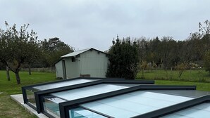 A swimming pool with a glass bottom and black frames, surrounded by stone tiles.