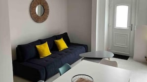 A modern living room with a sofa, a dining table, and a hanging light fixture.