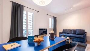 Una sala de estar moderna con una mesa azul, sillas negras, un sofá azul y un televisor.