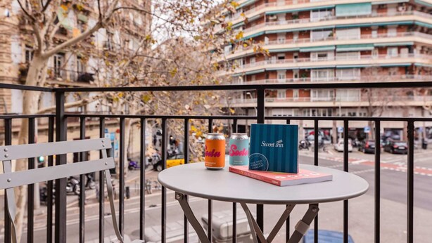 Un balcón con una mesa, dos latas y un libro.