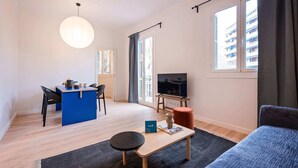 Un espacio habitable compacto con kitchenette, una zona de comedor, una sala de estar con sofá, televisión y ventanas amplias con vistas al exterior.