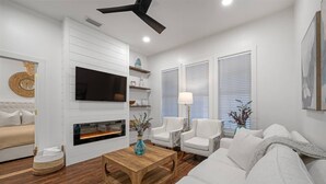 A modern living room with a fireplace, white sofas, a coffee table, and a TV mounted on the wall.