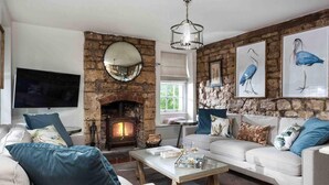 A living room with a stone fireplace, a flat-screen TV, and a sofa set. - Beautiful Cotswold Cottage in Rodborough, Stroud (Stroud)