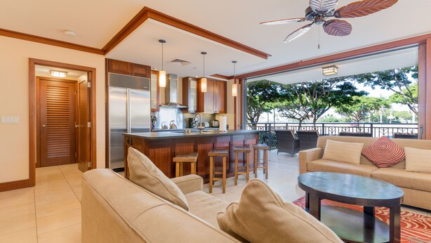 Una cocina moderna con barra, zona de comedor con sofá y mesa, y un balcón con mobiliario exterior.