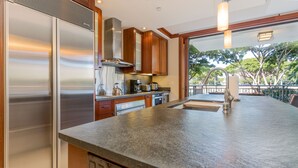 Una cocina moderna con electrodomésticos de acero inoxidable, armarios de madera y una isla grande con pileta.