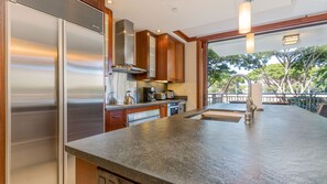 Una cocina moderna con electrodomésticos de acero inoxidable, armarios de madera y una isla grande con pileta.