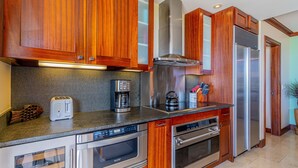 A modern kitchen with wooden cabinets, stainless steel appliances, and a granite countertop.