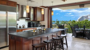 Uma cozinha com uma ilha grande, banquetas e vista para o oceano.