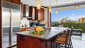 Una cocina moderna con una isla grande, electrodomésticos de acero inoxidable y vistas a la ciudad.