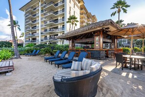 Ein Strandhotel mit mehreren Balkonen, Sitzgelegenheiten im Freien und einer Bar.