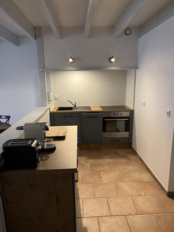 Une cuisine compacte dotée d’un plan de travail en bois, d’un four encastré et d’un évier.