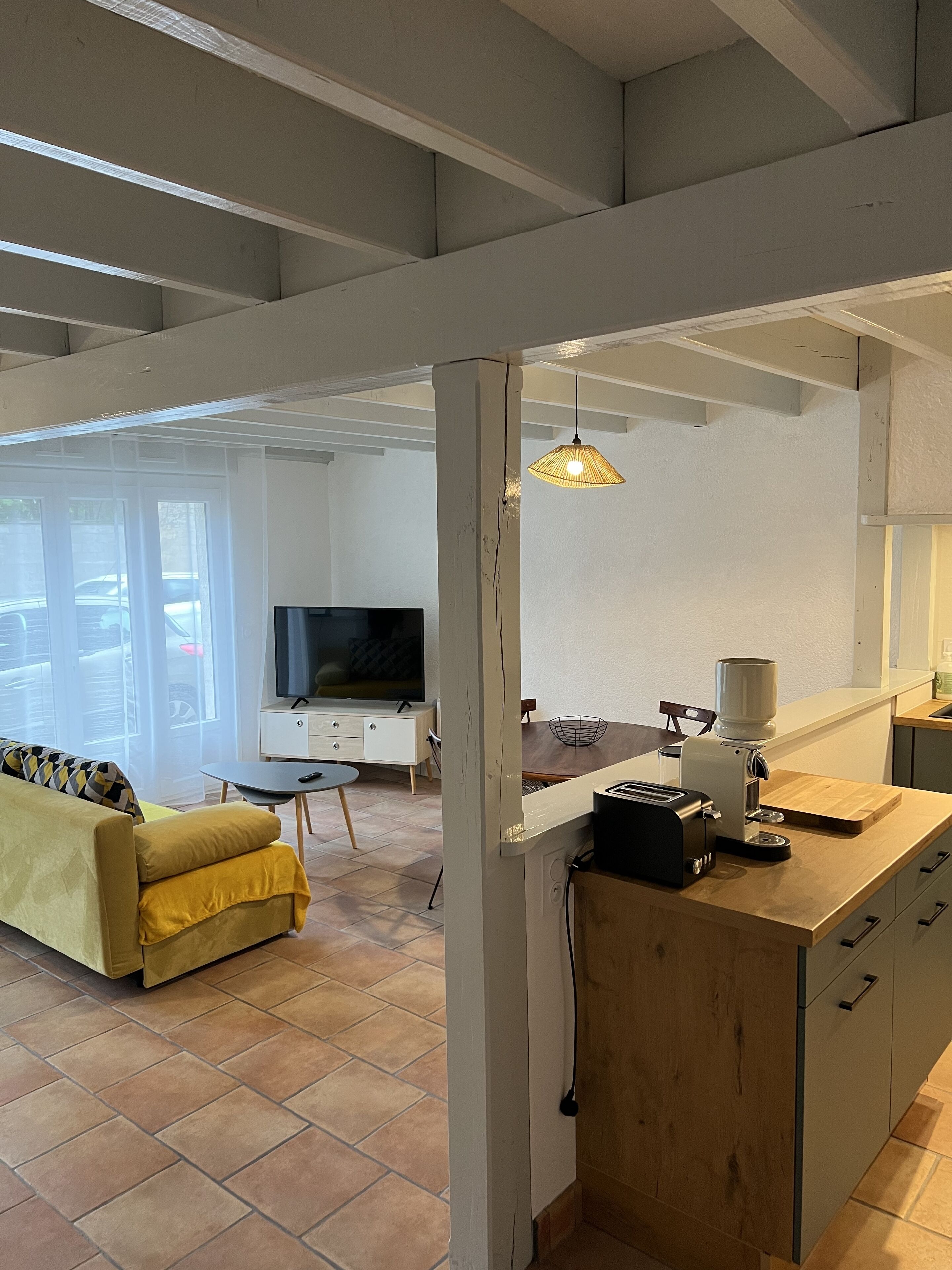 A modern living room with a sofa, a coffee machine, and a TV.