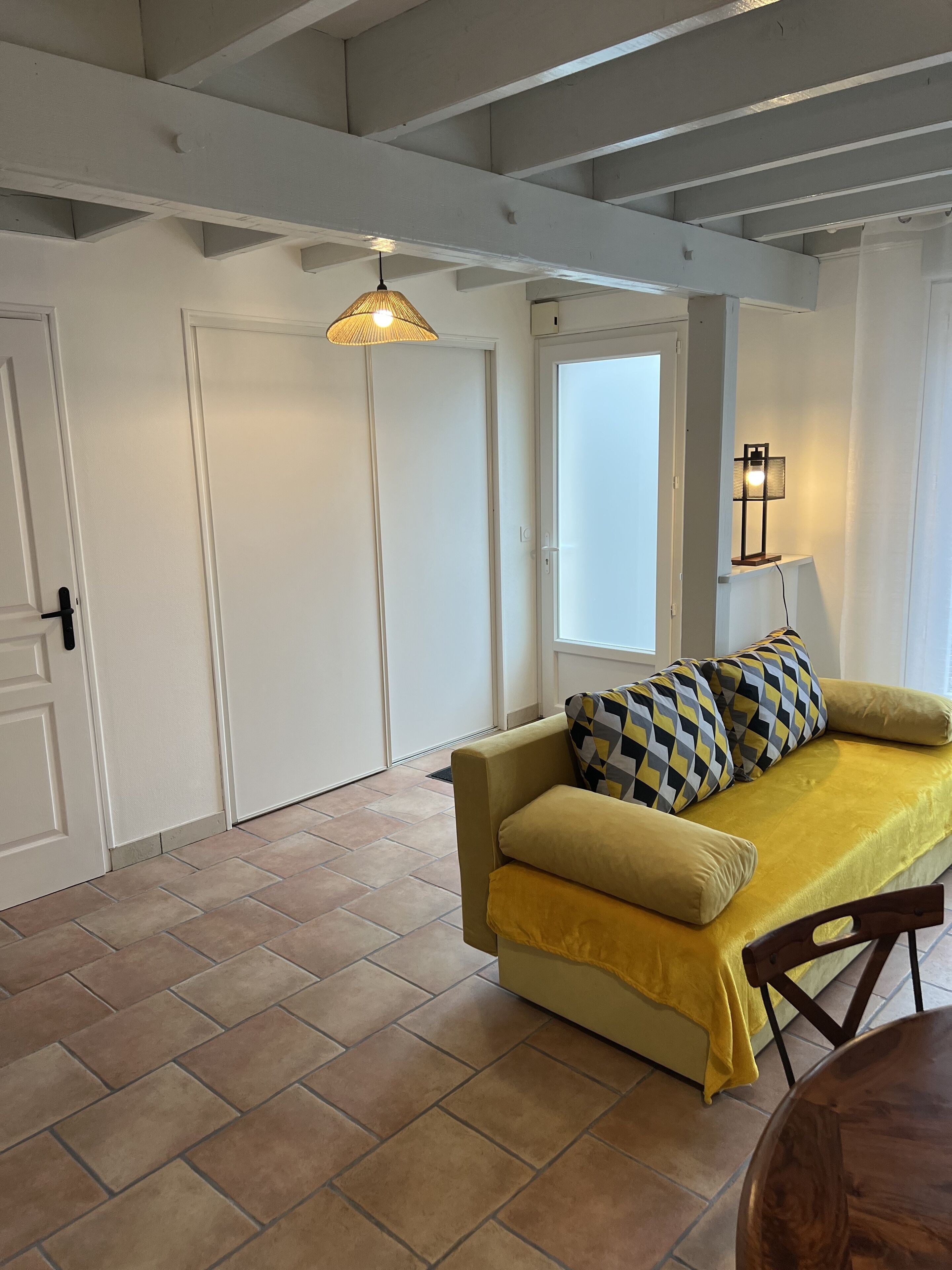 A room with a sofa, a lamp, and a window.