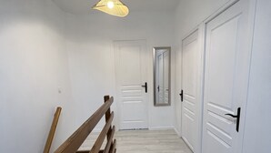 A hallway with white walls, a wooden bench, and a hanging light fixture. - Charmante Maison en Brenne (Vendœuvres)