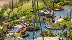 A resort with a pool area, lounge chairs, and tropical landscaping.