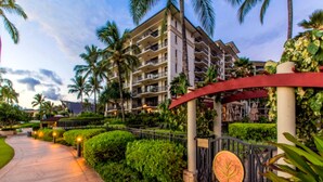 A hotel entrance with a paved pathway, well-maintained hedges, and a gated entrance with a decorative sign.