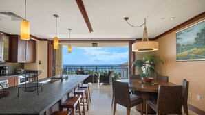 A modern kitchen with a large island, bar stools, and a dining area with a round table and chairs.