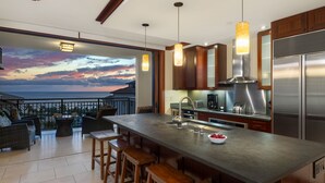 A modern kitchen with a large island, stainless steel appliances, and pendant lighting.