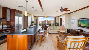 Una cocina moderna con una isla central, un comedor con vistas y una sala de estar con televisor.
