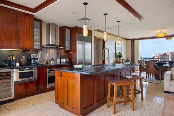 A modern kitchen with wooden cabinets, stainless steel appliances, and a large island with stools.