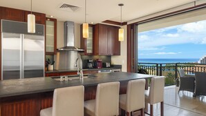 A modern kitchen with a large island, bar stools, and a view of the ocean. - Ko Olina Beach Villas O1121: Luxurious Villa w/Golf Course & Ocean Views (Kapolei)