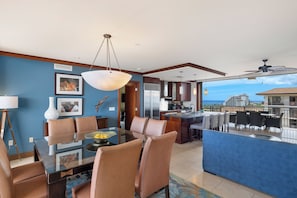 A modern dining area with a glass table, leather chairs, and a view of the ocean.