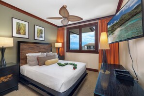 A hotel room with a bed, a ceiling fan, a TV, and a window with curtains.