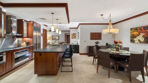 A modern kitchen with a central island, stainless steel appliances, and a dining area with a round table and chairs.