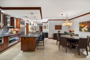 A modern kitchen with a central island, stainless steel appliances, and a dining area with a round table and chairs.