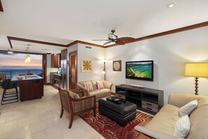 A modern living room with a sofa, ottoman, and dining area.
