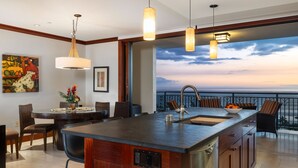 Una cocina moderna con una isla grande, luces colgantes y vistas al océano.