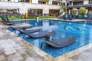 A swimming pool with lounge chairs and a stone building in the background.